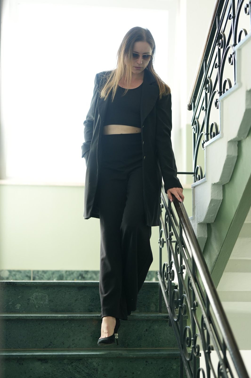 Irina le Fey im schwarzen Anzug auf einer Treppe